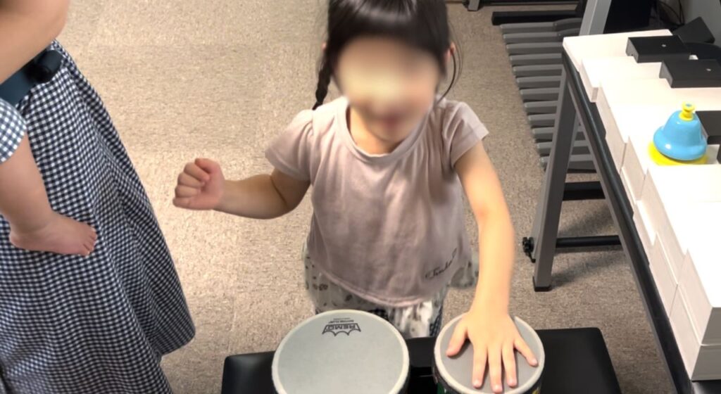 打楽器でリズム叩きをする幼児